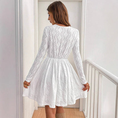Frau in weißem Spitzenkleid, Rückansicht, steht in modernem Innenraum. Elegantes Design, lange Ärmel, modische Damenbekleidung, stilvoller Look.