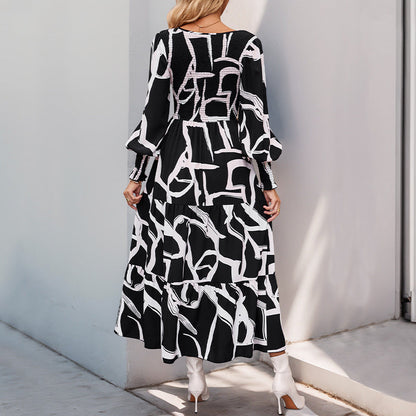 Frau in langem, schwarz-weiß gemustertem Kleid mit langen Ärmeln und weißen Stiefeletten, steht vor einer grauen Wand. Modetrend, Damenmode, Herbstkleid.