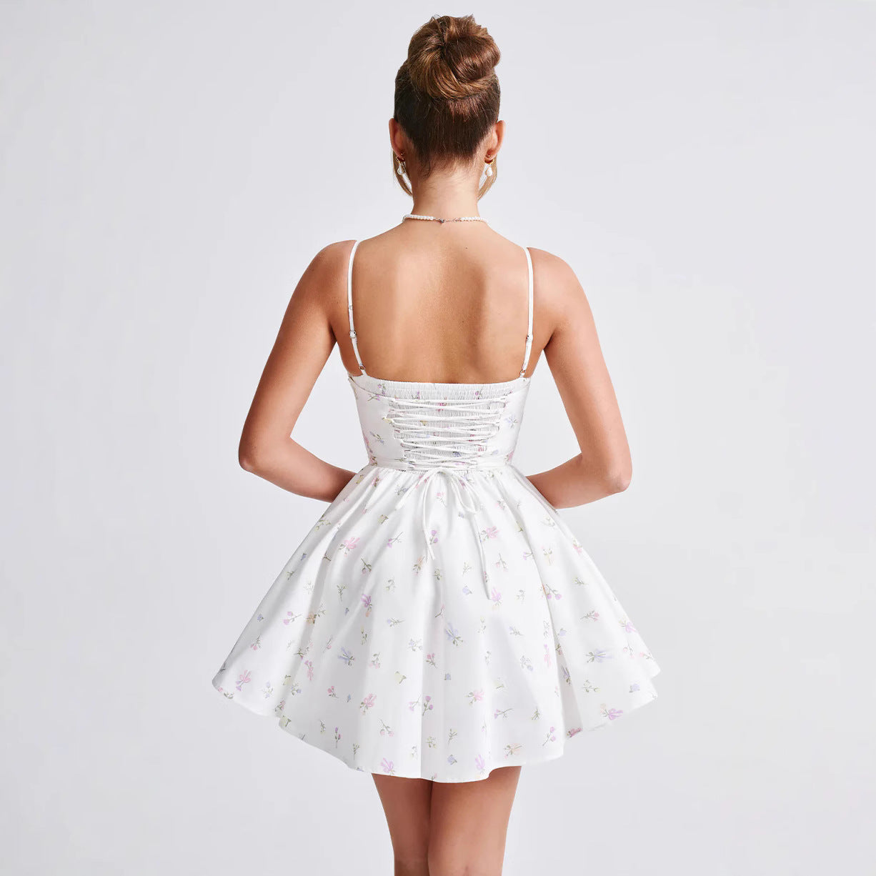 Rückansicht einer Frau in einem weißen, geblümten Sommerkleid mit Spaghettiträgern und Schnürung, eleganter Look, Mode für Damen, Sommerkleider 2023.