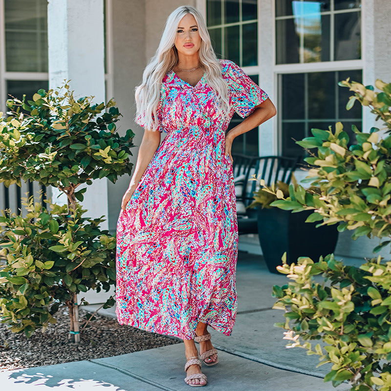 Frau in buntem Sommerkleid steht auf Terrasse, umgeben von Pflanzen. Mode, Sommerkleid, Outdoor, Damenmode, Freizeitkleidung.