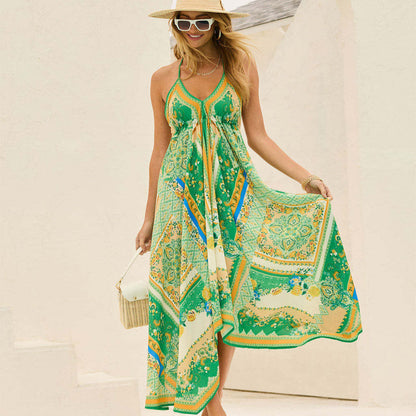 Blonde Frau in grünem Sommerkleid mit Paisley-Muster, Strohhut und Sonnenbrille, lächelnd vor hellem Hintergrund. Sommermode, Damenkleid, Strandlook.
