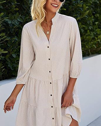 Blonde Frau in kariertem Sommerkleid mit Knopfleiste, lächelt im Freien. Modetrend 2023, lässiger Stil, Damenmode, Freizeitkleidung.