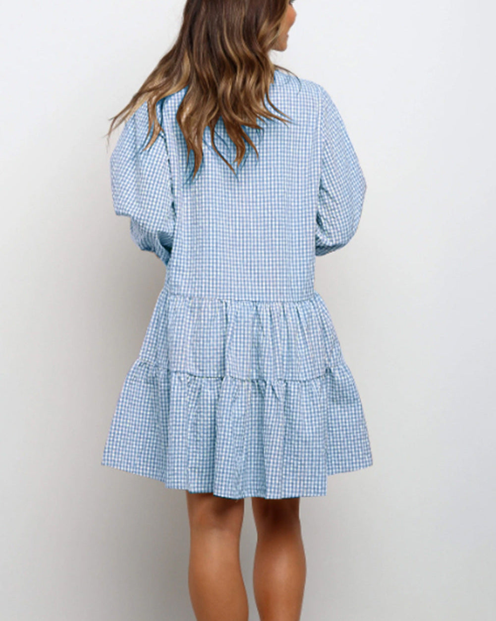 Frau in blau-weiß kariertem Kleid mit Rüschen, Rückansicht. Modetrend, Sommerkleid, Freizeitlook, Damenmode, stilvoll, bequem.