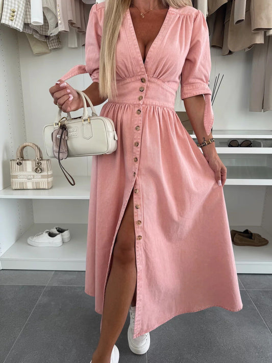 Frau in rosa Knopfkleid mit weißer Handtasche, vor einem Kleiderschrank mit beigen und weißen Kleidungsstücken. Elegante Mode, Sommerkleid.