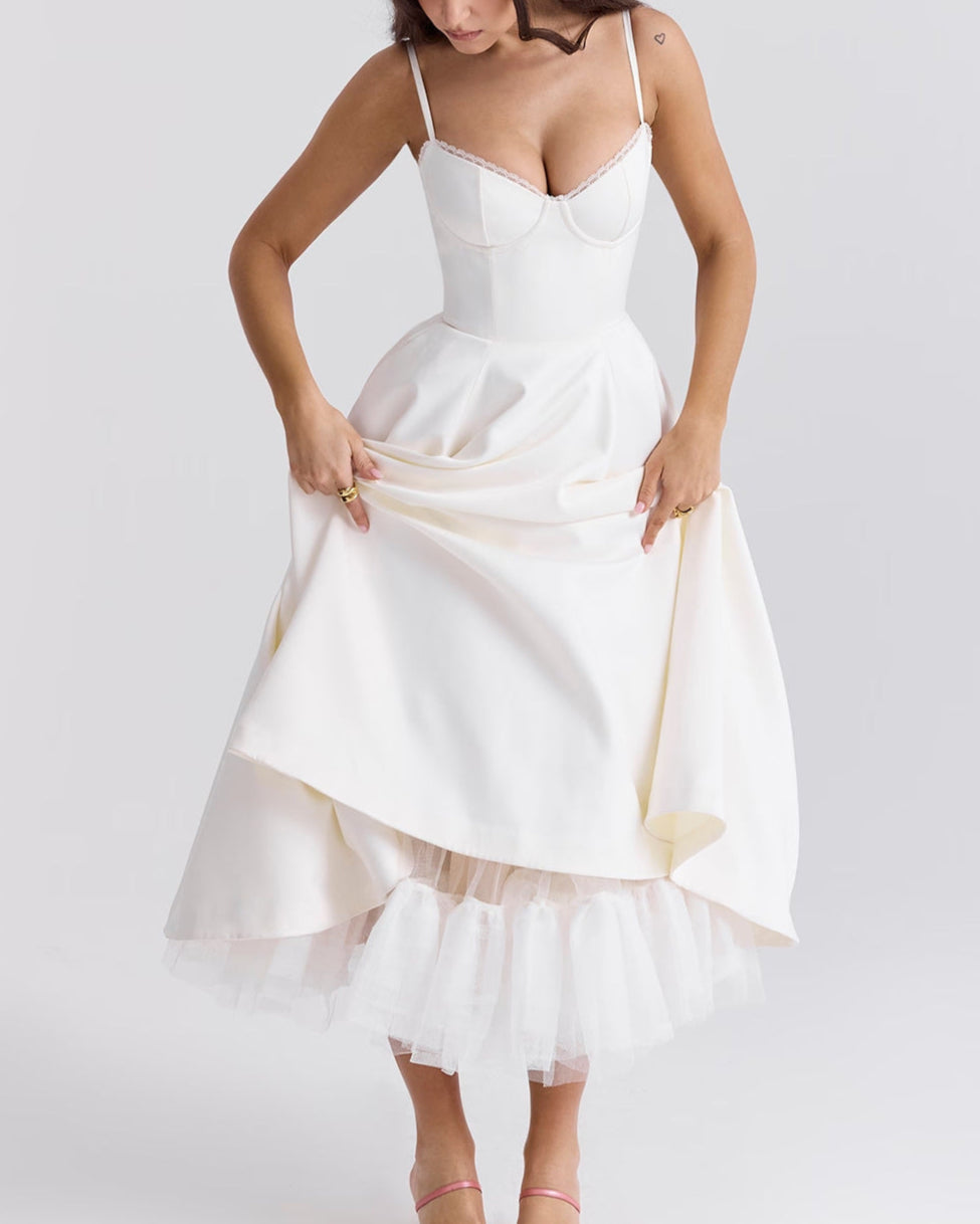 Frau in elegantem weißen Kleid mit Spaghettiträgern und Tüllunterrock, posiert vor neutralem Hintergrund. Mode, Abendkleid, Damenbekleidung.