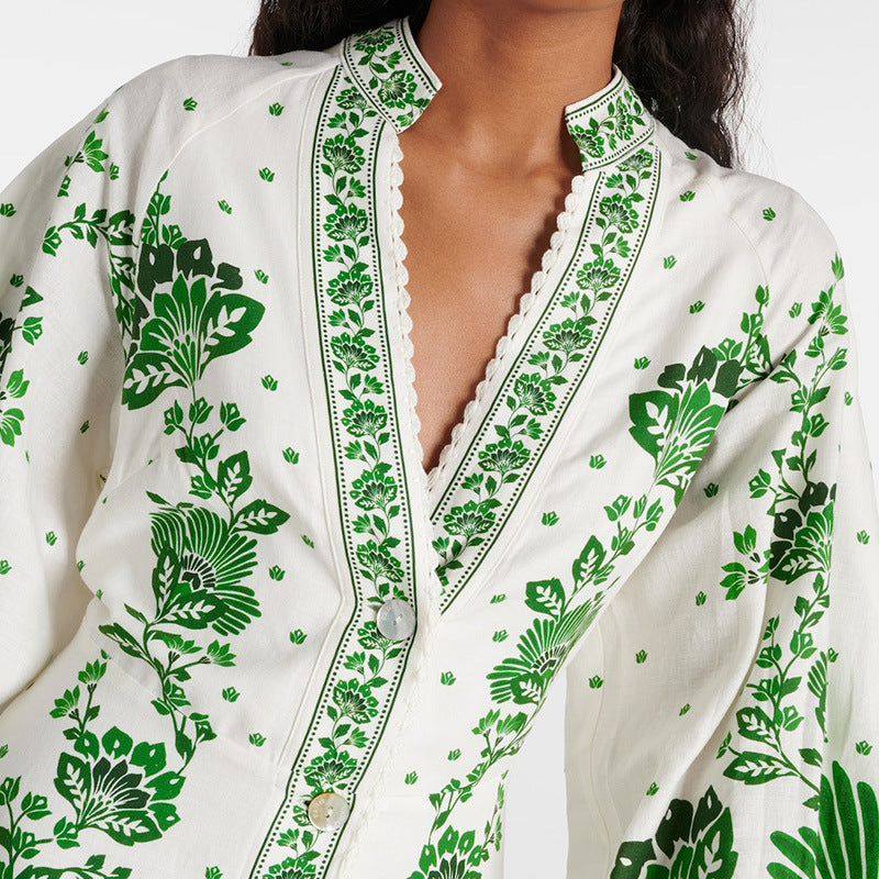 Frau in weißer Bluse mit grünem Blumenmuster, V-Ausschnitt und Knopfleiste. Modetrend, Damenmode, stilvolle Kleidung, Boho-Chic.
