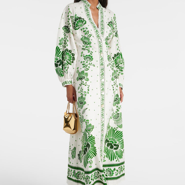 Frau in langem, weißem Kleid mit grünem Blumenmuster, hält goldene Handtasche. Elegantes Design, modisches Outfit, stilvolle Damenmode.