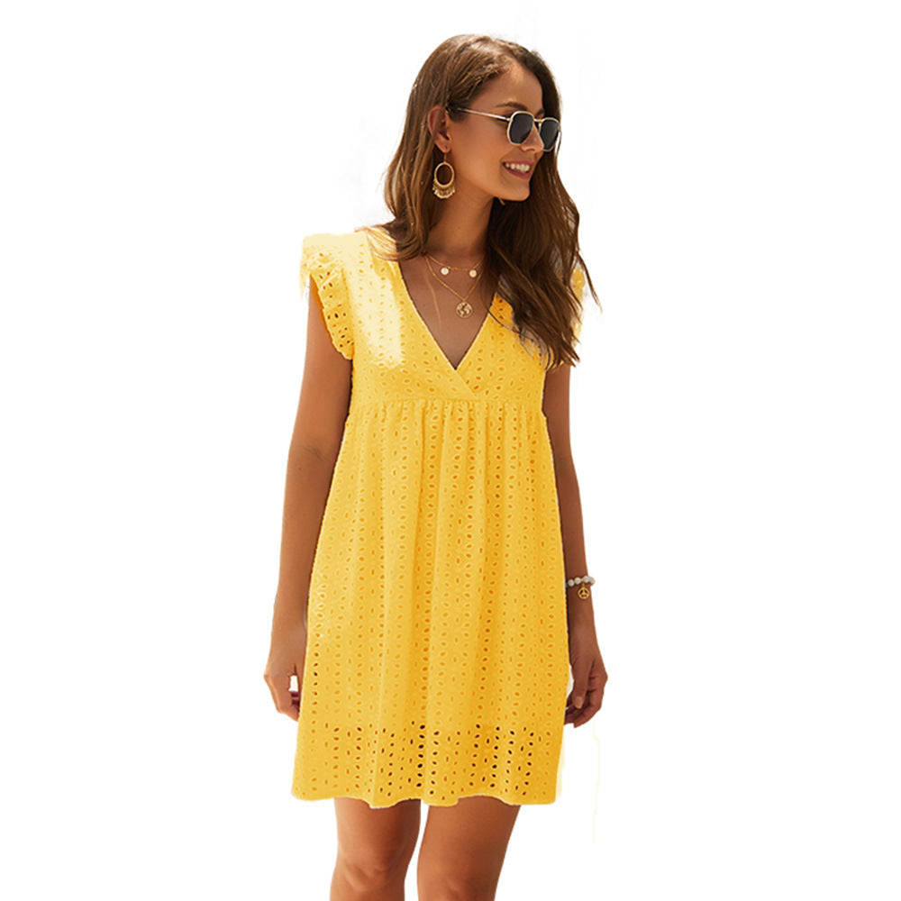Frau in gelbem Sommerkleid mit Spitzenmuster, Sonnenbrille und Schmuck. Perfekt für Strandmode und Sommeroutfits.