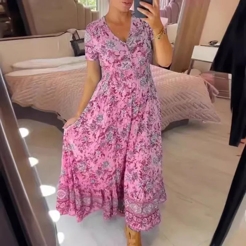 Frau in rosa geblümtem Maxikleid macht Selfie im Schlafzimmer. Elegantes Sommerkleid, florales Muster, modische Damenbekleidung.