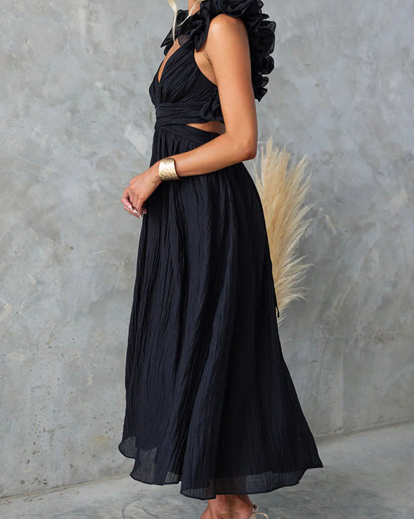 Schwarzes, ärmelloses Maxikleid mit Rüschen und Cut-Out-Details, getragen von einer Frau vor grauer Wand. Elegantes Abendkleid, modisches Design.