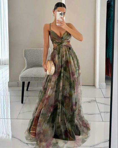 Frau im eleganten, ärmellosen Abendkleid mit Blumenmuster, hält eine runde Clutch, steht vor einem Spiegel. Perfekt für Gala oder Hochzeit.