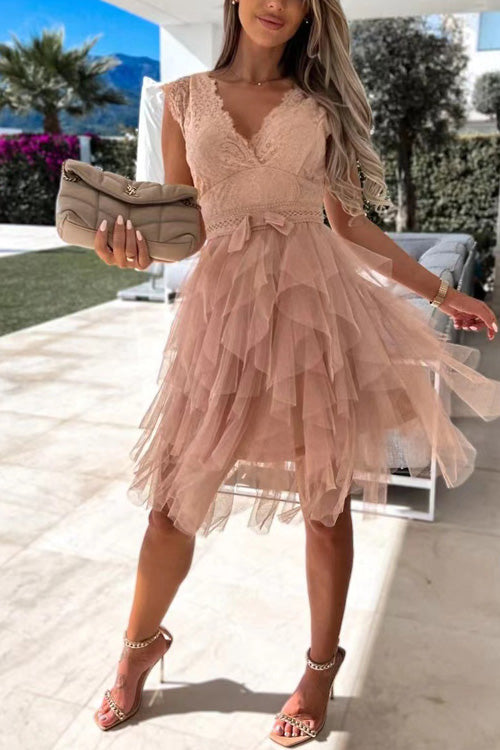 Frau in rosa Spitzenkleid mit Rüschen, hält eine beige Clutch. Sommermode, elegantes Outfit, stilvolle Abendgarderobe im Freien.