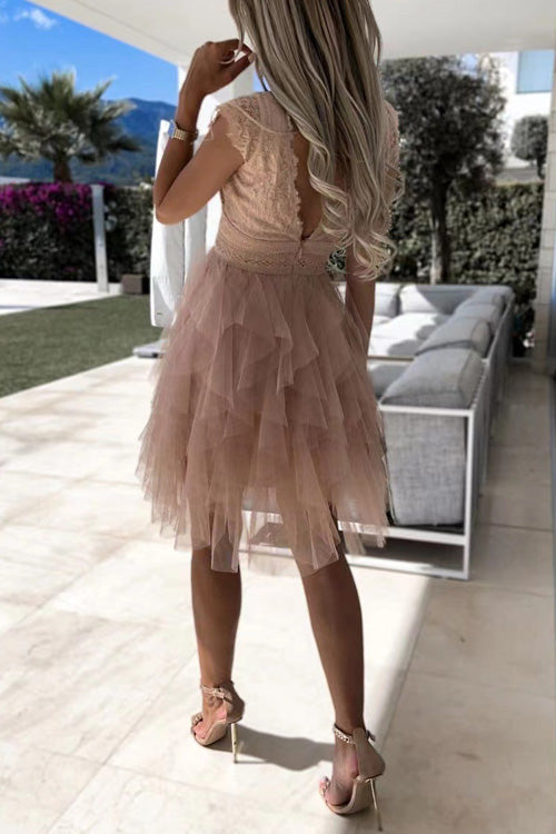 Frau in elegantem, rosa Tüllkleid mit Rüschen steht auf Terrasse; Sommermode, Abendkleid, stilvolle Kleidung, luxuriöse Umgebung.
