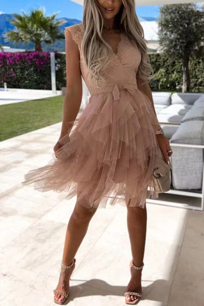 Frau in elegantem, ärmellosem, rosa Tüllkleid mit Rüschen, steht auf Terrasse. Sommermode, stilvolle Abendgarderobe, modisches Outfit.