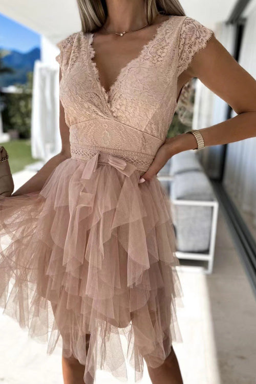 Frau in elegantem, rosa Spitzenkleid mit Tüllrock, V-Ausschnitt und Schleife, steht auf Terrasse. Perfekt für Sommermode und Abendveranstaltungen.