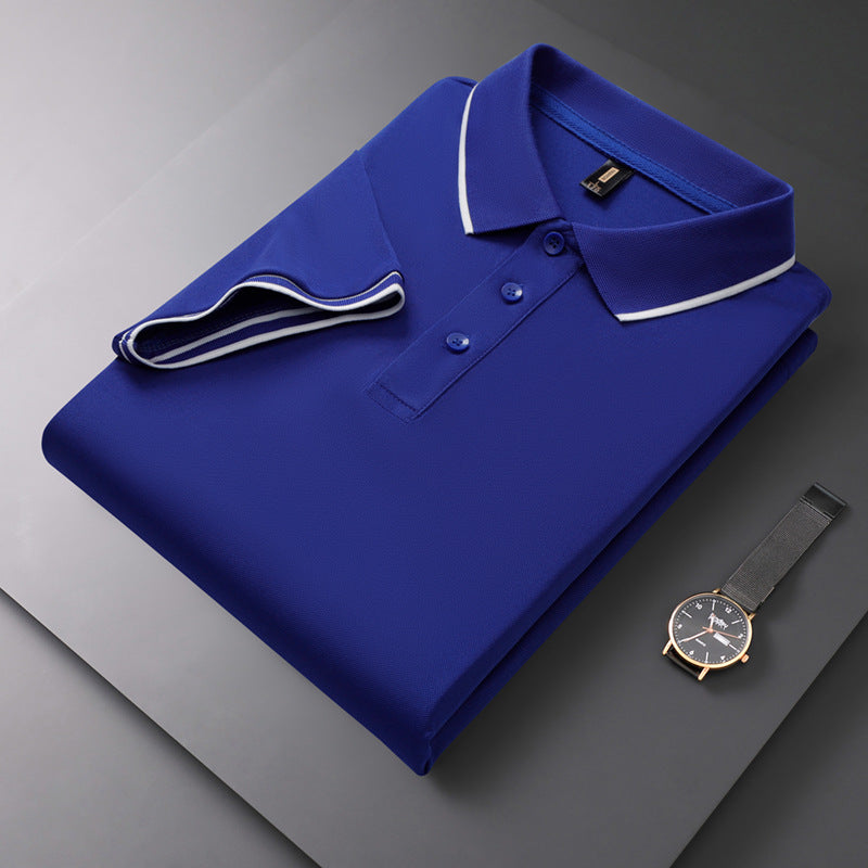 Blaues Polohemd mit weißen Akzenten, gefaltet auf grauem Hintergrund, neben einer eleganten Armbanduhr. Mode, Herrenbekleidung, Accessoires.
