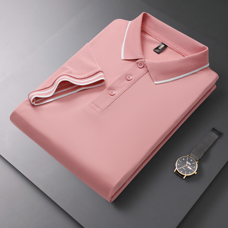 Gefaltetes rosa Polohemd mit weißem Kragen auf grauem Hintergrund, daneben eine elegante Armbanduhr. Mode, Herrenbekleidung, Accessoires.
