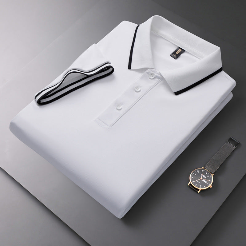 Gefaltetes weißes Polohemd mit schwarzem Kragen und Knopfleiste, daneben eine elegante Armbanduhr auf grauem Hintergrund.