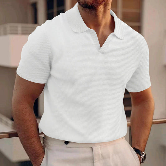 Mann in weißem Polohemd und beiger Hose auf Balkon. Sommermode, Herrenbekleidung, stilvoll, lässig, modern.