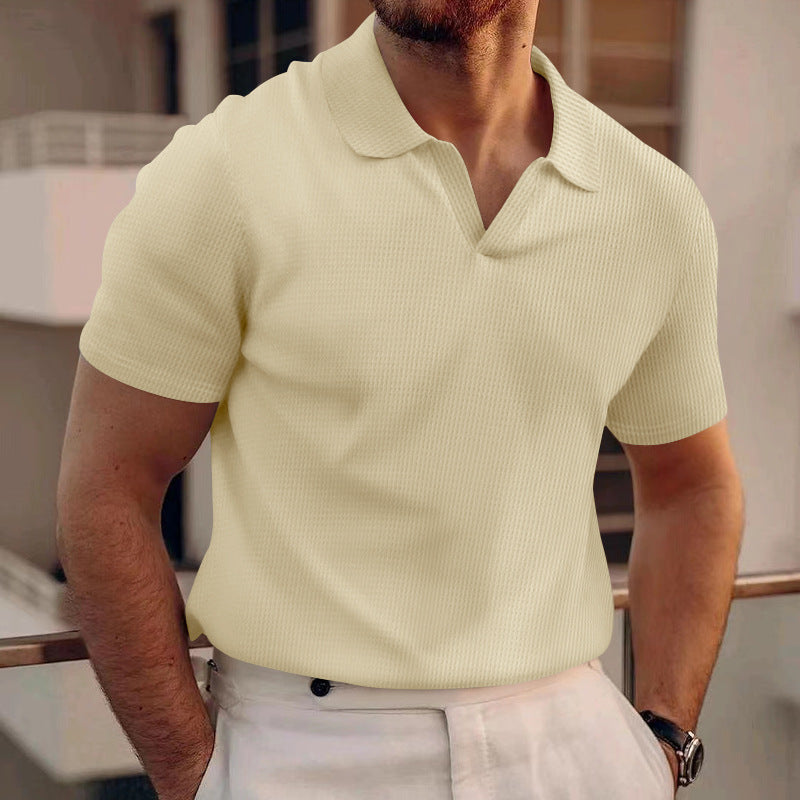 Mann in cremefarbenem Polohemd und weißen Hosen auf Balkon. Sommermode, Herrenbekleidung, eleganter Freizeitlook, stilvoller Auftritt.