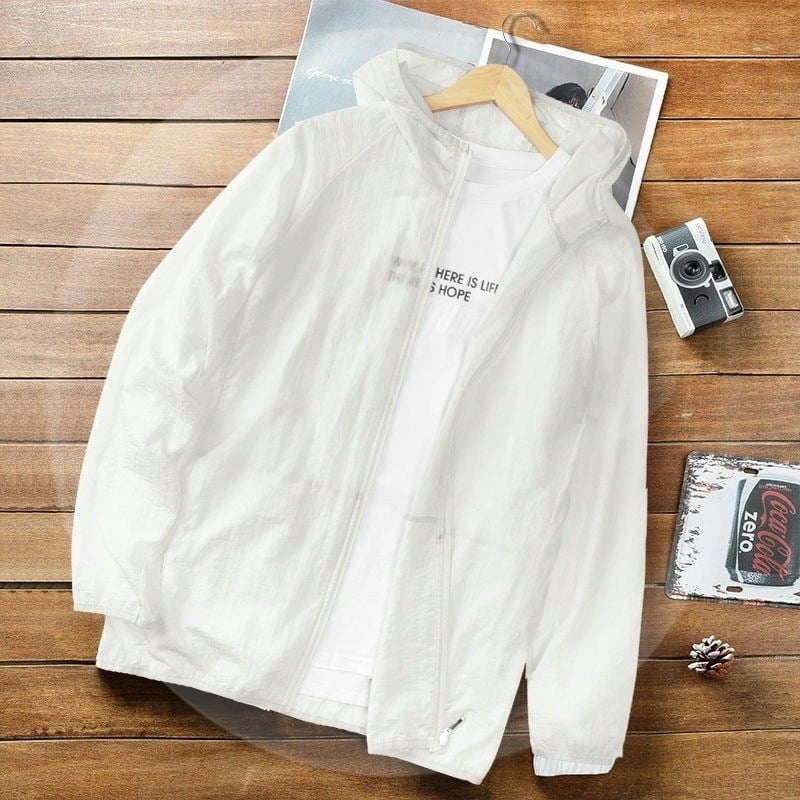 Weiße Herrenjacke mit Kapuze auf Holztisch, daneben Kamera und Coca-Cola-Deckel. Modische Freizeitkleidung, ideal für Frühling und Herbst.