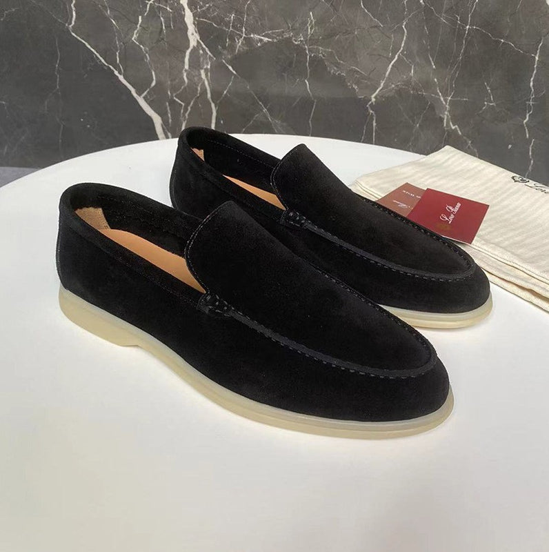 Schwarze Wildleder-Loafer auf weißem Tisch, elegante Herrenschuhe mit beiger Sohle, stilvoll und modern, ideal für formelle Anlässe.