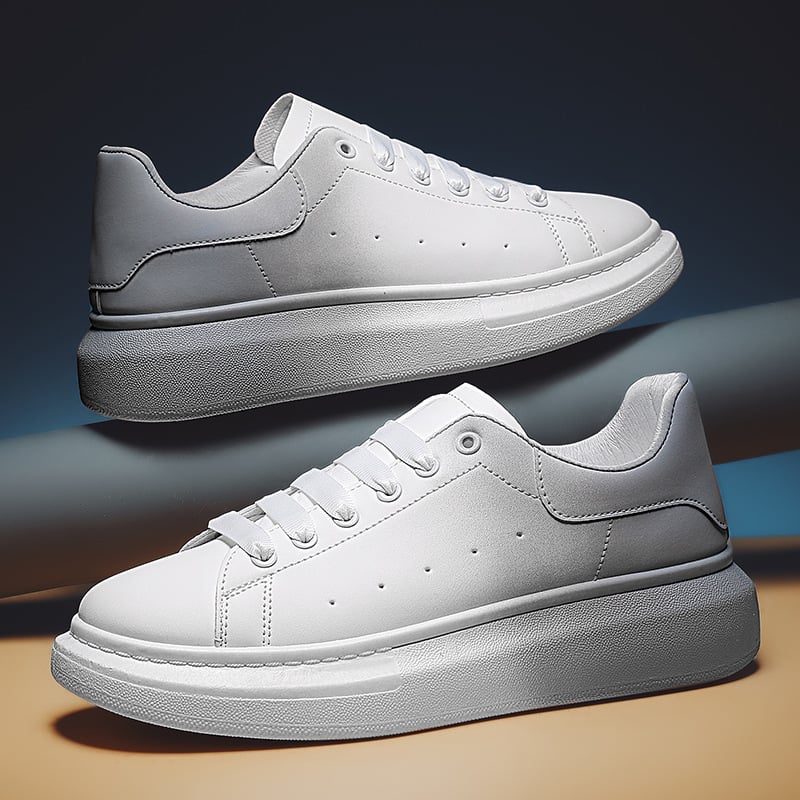 Weiße Sneaker mit dicker Sohle, seitlich dargestellt auf blauem Hintergrund. Modische Turnschuhe, minimalistisch, sportlich, trendig.