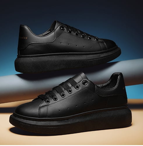 Schwarze Leder-Sneaker mit dicker Sohle, stilvoll und modern, auf blauem Hintergrund. Perfekt für urbane Mode und Streetwear-Looks.