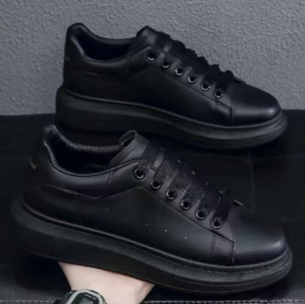Schwarze Leder-Sneaker mit dicker Sohle, minimalistischem Design und Schnürung, auf schwarzem Hintergrund präsentiert.