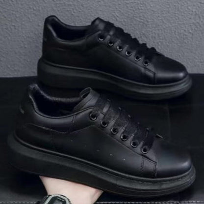 Schwarze Leder-Sneaker mit dicker Sohle, minimalistischem Design und Schnürung, auf schwarzem Hintergrund präsentiert.
