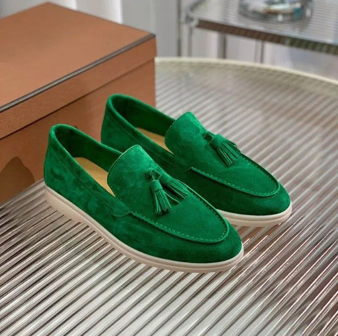 Grüne Wildleder-Loafer mit Quasten, stilvoll auf einem Tisch präsentiert. Elegante Herrenschuhe, ideal für modische Anlässe und Freizeitkleidung.