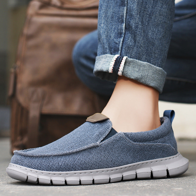 Blaue Herren-Slipper aus Stoff, kombiniert mit Jeans, ideal für Freizeit und Alltag. Bequeme, rutschfeste Sohle. Perfekt für stilvolle Herrenmode.