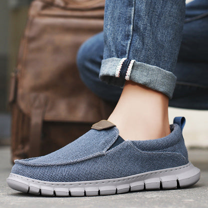 Blaue Herren-Slipper aus Stoff, kombiniert mit Jeans, ideal für Freizeit und Alltag. Bequeme, rutschfeste Sohle. Perfekt für stilvolle Herrenmode.