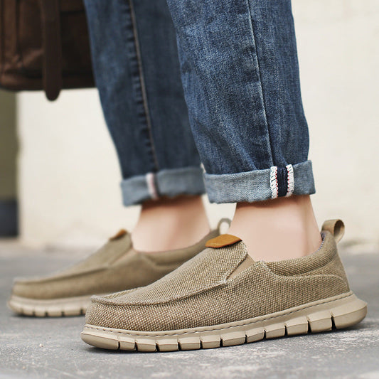 Beige Herren-Slipper aus Leinen mit flexibler Sohle, getragen zu hochgekrempelten Jeans. Bequeme Freizeitschuhe für den Alltag.