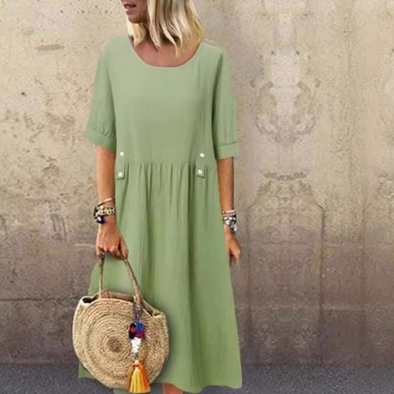Frau in grünem Sommerkleid mit Strohtasche vor beiger Wand. Modetrend, lässiger Stil, Sommermode, Damenbekleidung, Accessoires.