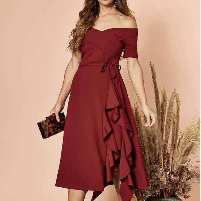 Frau in schulterfreiem, weinrotem Kleid mit Rüschen, hält eine Clutch. Elegantes Abendoutfit, Mode für besondere Anlässe, stilvoller Look.
