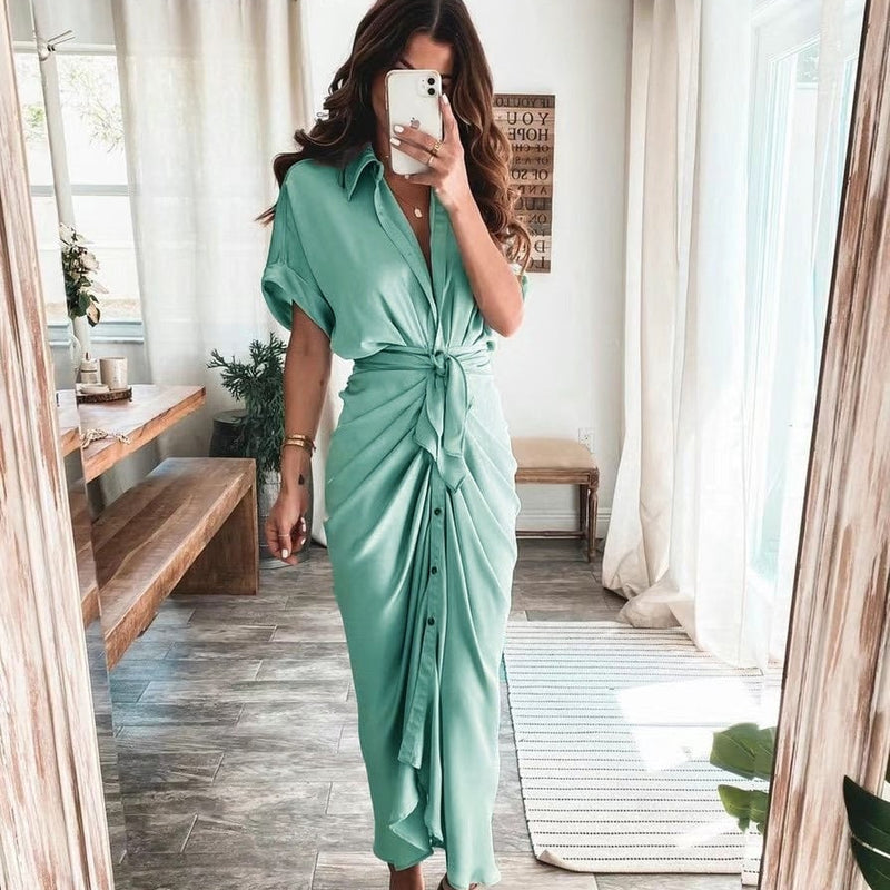 Frau in mintgrünem, geknotetem Hemdkleid, steht in modernem Wohnzimmer, macht Selfie. Stilvolle Mode, Sommerkleid, Innenarchitektur.
