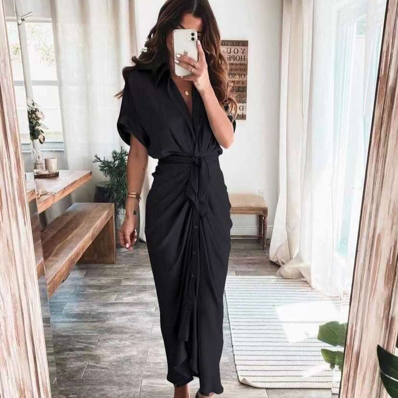 Frau in elegantem schwarzen Kleid, steht in modernem Wohnzimmer, macht Selfie. Stilvolle Mode, Innenarchitektur, Tageslicht, Holzdetails.