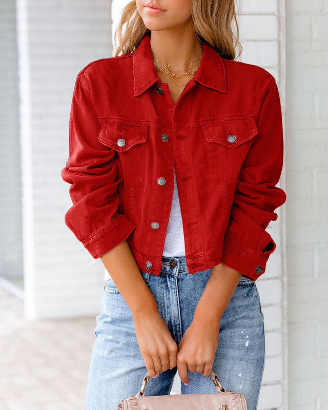 Frau in roter Jeansjacke, weißem T-Shirt und blauer Jeans, hält eine beige Handtasche. Modetrend, lässiger Stil, Damenmode.