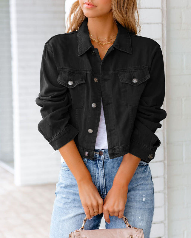 Frau in schwarzer Jeansjacke, weißem T-Shirt und blauer Jeans vor weißer Wand. Modetrend, lässiger Stil, Damenbekleidung, Streetwear.