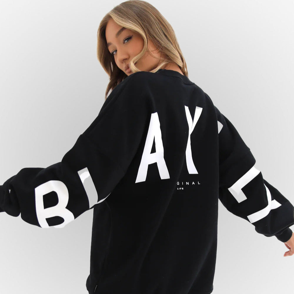 Junge Frau in schwarzem Blakely-Sweatshirt mit weißem Logo, Rückansicht. Modetrend, Streetwear, lässiger Stil.