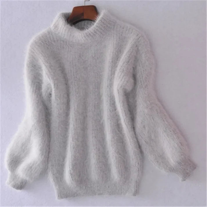 Grauer, flauschiger Damenpullover aus Angorawolle mit langen Ärmeln und Rundhalsausschnitt auf einem Kleiderbügel vor weißem Hintergrund.