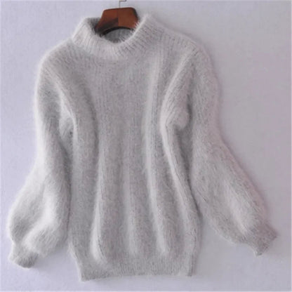 Grauer, flauschiger Damenpullover aus Angorawolle mit langen Ärmeln und Rundhalsausschnitt auf einem Kleiderbügel vor weißem Hintergrund.