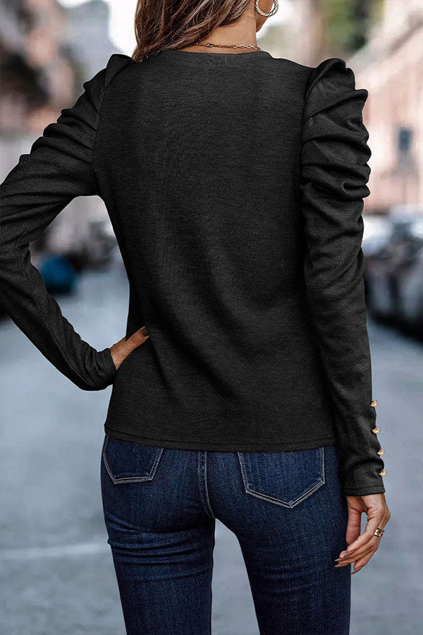 Frau in schwarzem Langarmshirt mit Rüschenärmeln und blauen Jeans, Rückansicht, städtische Straße im Hintergrund. Modetrend, Damenbekleidung.