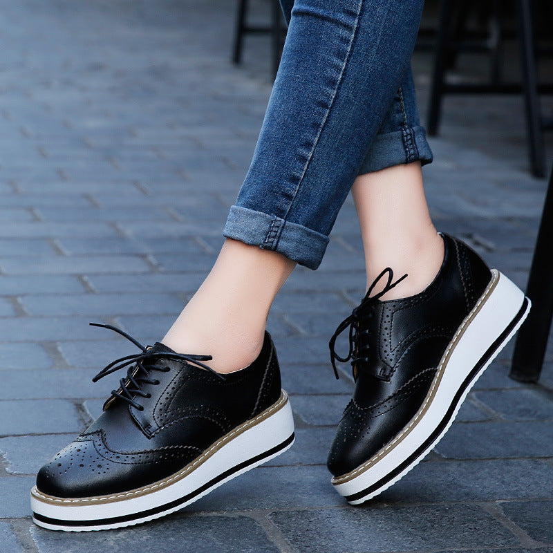 Schwarze Damen-Brogues mit Plateau, geschnürt, aus Leder, kombiniert mit blauen Jeans. Modische Schuhe für Herbst, ideal für urbanen Stil.