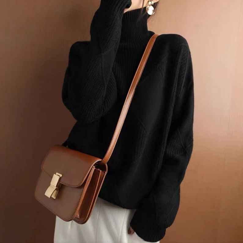 Frau in schwarzem Rollkragenpullover mit brauner Umhängetasche, modisch, elegant, Herbstmode, Damenbekleidung, stilvoller Look.