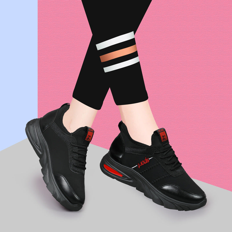 Schwarze Damen-Sneaker mit rotem Akzent, getragen von Person in schwarzer Leggings vor rosa-blauem Hintergrund. Bequeme Sportschuhe, modisch.