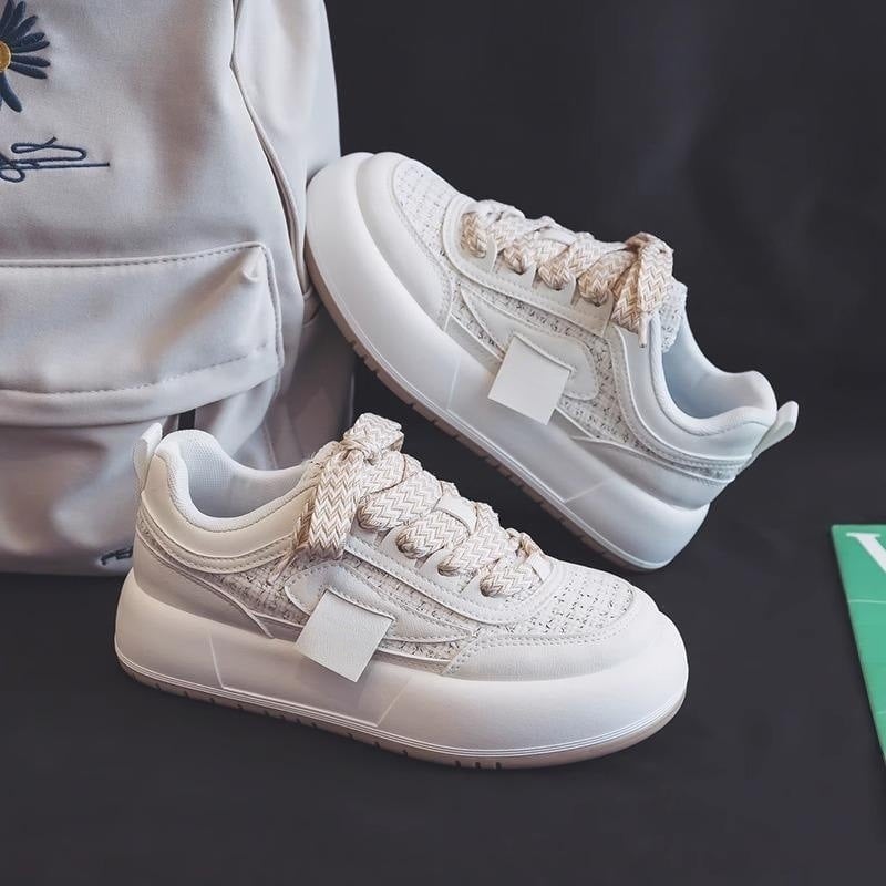 Weiße Sneaker mit dicker Sohle und geflochtenen Schnürsenkeln, neben einem weißen Rucksack. Moderne Sportschuhe, stilvoll und bequem.