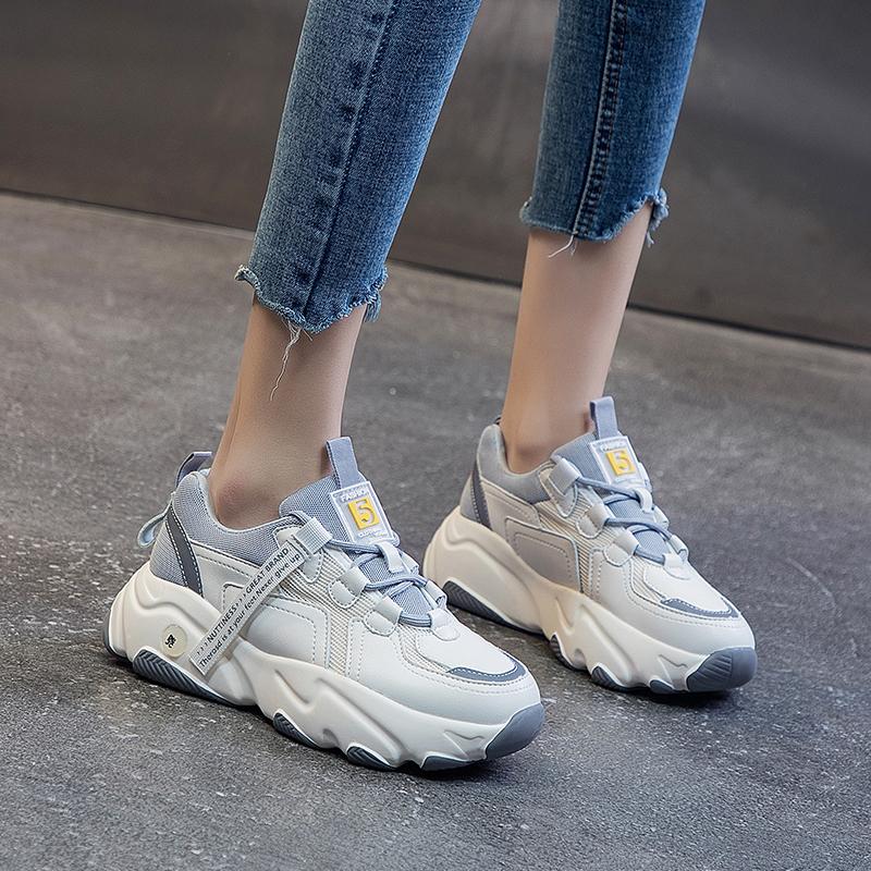 Damen Sneaker in Weiß und Grau, klobiges Design, getragen mit blauen Jeans. Modische Sportschuhe, ideal für Freizeit und Streetwear.