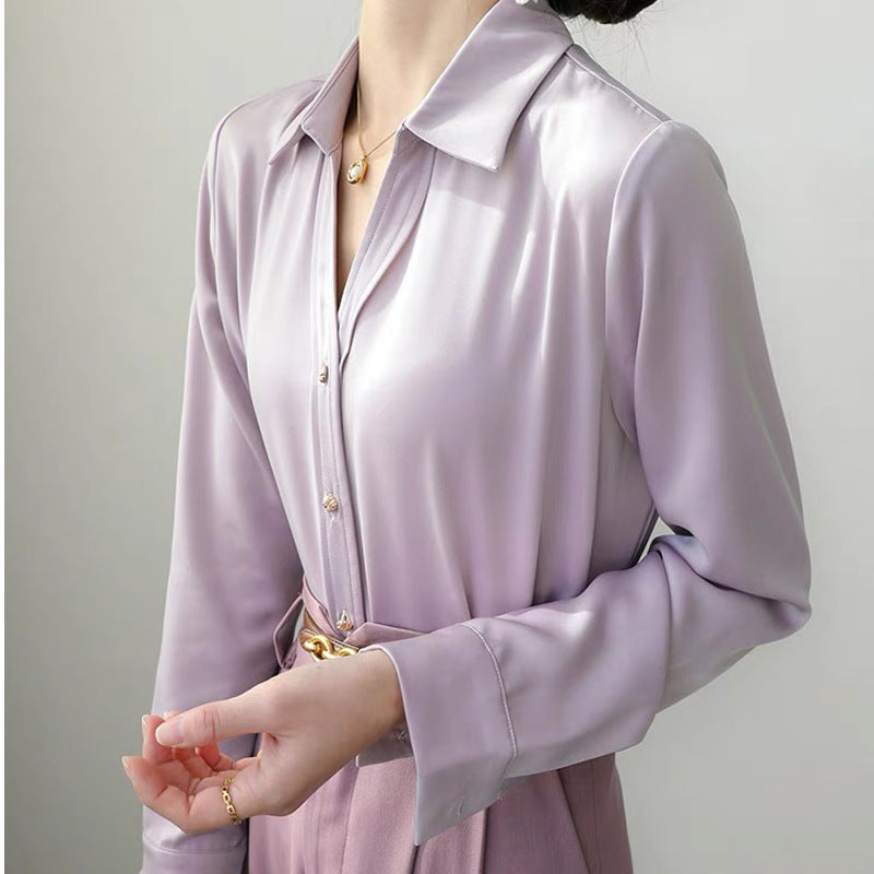Elegante Frau in lila Satinbluse mit goldenen Knöpfen und Gürtel, modisches Outfit, stilvolle Damenmode, luxuriöser Stoff, Bürolook.
